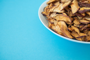 dried apples in white plate on blue background