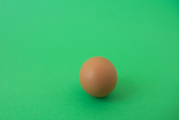 brown raw egg on green background