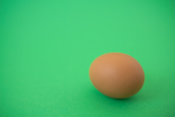 brown raw egg on green background