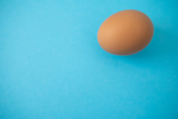 brown raw egg on blue background