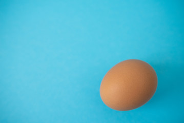 brown raw egg on blue background