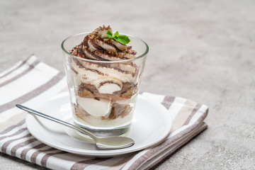 Classic tiramisu dessert in a glass on concrete background