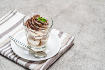 Classic tiramisu dessert in a glass on concrete background