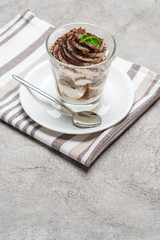 Classic tiramisu dessert in a glass on concrete background