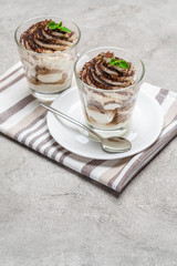 Classic tiramisu dessert in a glass on concrete background