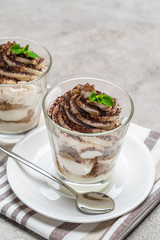 Classic tiramisu dessert in a glass on concrete background