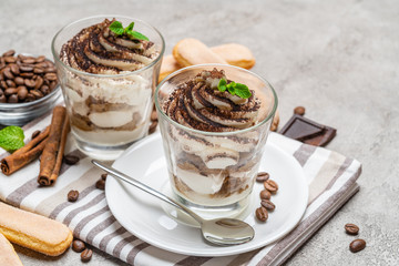 Classic tiramisu dessert in a glass on concrete background