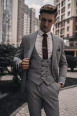 Young handsome businessman posing on city street. Male model on buildings background. Stylish full suit. Success. Business concept