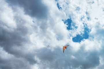 Naklejka na ściany i meble A large kite floats high in the sky among the clouds against the blue sky and the bright summer sun and it is controlled by two white ropes going to the ground