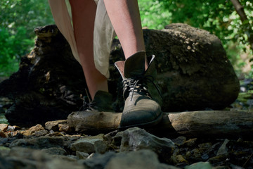 legs of a young girl in strange vintage boots during a walk in the woods on a warm summer day