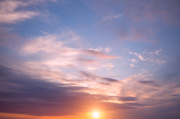 Naklejka na ściany i meble Sunset on the sky, bright sun and colorful clouds.