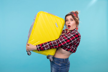 Frightened young beautiful woman in vintage clothes holding a yellow suitcase in her hands posing...