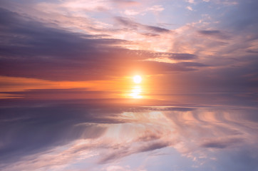 Fototapeta na wymiar Sunset on the sky, bright sun and colorful clouds over the calm sea.