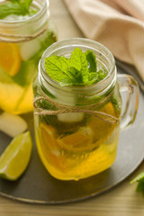 Homemade lemonade with lime, mint in a mason jar on a wooden rustic table. Summer drinks.