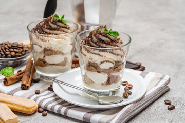 Classic tiramisu dessert in a glass and coffee makeron concrete background