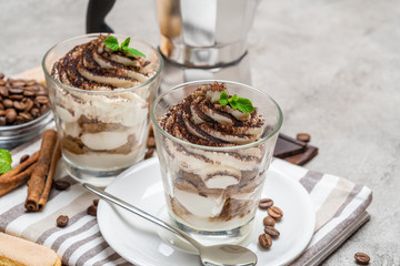 Classic tiramisu dessert in a glass and coffee makeron concrete background