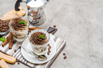 Classic tiramisu dessert in a glass and coffee makeron concrete background