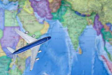 Fototapeta na wymiar Toy plane over world map. Air trip to India. travel by plane, booking tickets, flight by aircraft concept