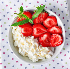 White bowl with fresh red ripe strawberries and natural cottage cheese