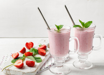 Glass of fresh strawberry and yogurt smoothie on white wooden table