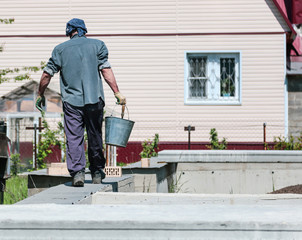 Worker with buckets of concrete at a house construction