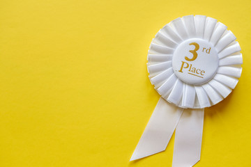 3rd place white ribbon rosette on yellow