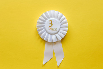 3rd place white ribbon rosette on yellow