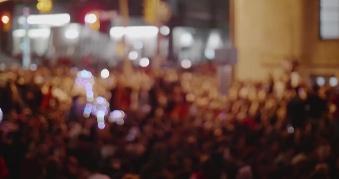 Massive defocused crowd downtown at night. Cinematic 4K footage.
