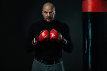 Businessman and sportsman in suit, man boxer in gloves with boxing punching bag. Trainings and