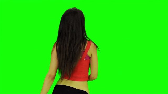 Attractive sexy woman dancing back in front of a green screen with black legging and a red top. Static medium shot. 4K.