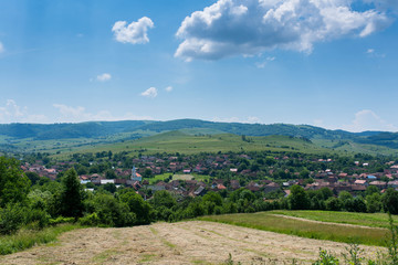 Fototapeta na wymiar Small Transylvanian village at summertime , blue sky with white clouds in the background.