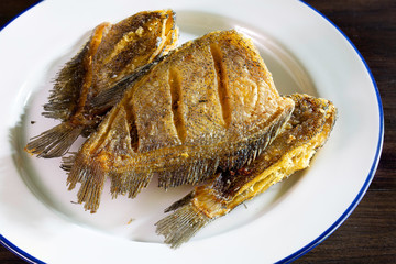Fried dry salt fish (Thai language -pla salid) in white dish on dark background