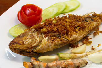 Fry fish with spices and herbs which has turmeric, in white dish, Thai food