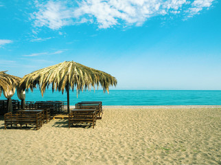 Panoramic view of sandy beach with outdoors cafe at blue sea and sky background