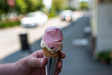 Caucasian boy holding delicious cone filled with ice cream, shallow depth of field.