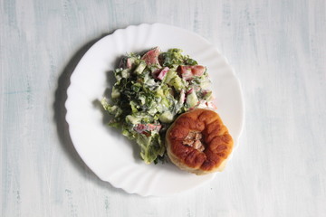 Meat pie belyash on white plate with vegetable salad