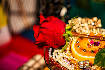 Colse up of Rose in front of Orange Decorated With Jewellery and Natural Pearls