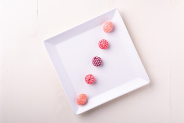 Five candy canes sweets in form of juicy berries on white plate on white background isolated top view