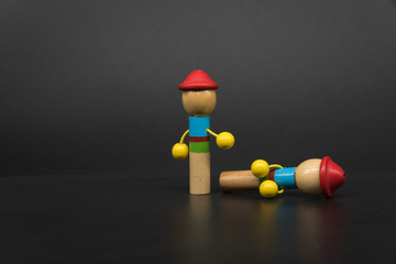 2 colored puppets creatively placed on a black background, one standing, one lying down