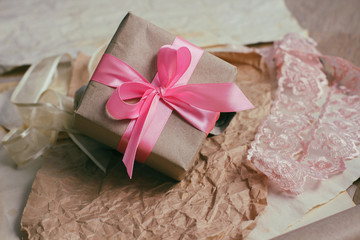 Gift box with satin ribbon. Packaging process. Wedding presents. Craft paper background. 