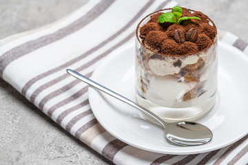 Classic tiramisu dessert in a glass on concrete background