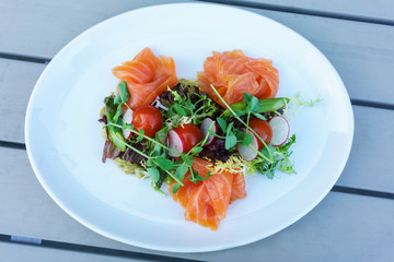 Salmon salad with mixed vegetable on white plate