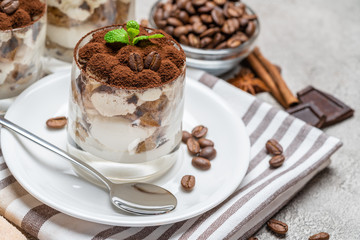 Classic tiramisu dessert in a glass on concrete background
