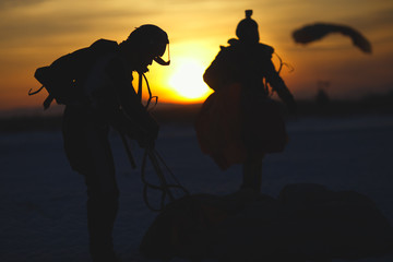 Silhouettes of skydivers after landing against the backdrop of sunset, closeup. Parachute jumps.