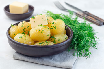 Naklejka na ściany i meble New young boiled potato topped with melted butter and chopped dill, in ceramic bowl, horizontal