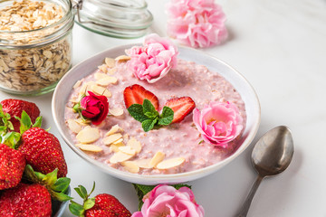 romantic healthy breakfast. overnight strawberry oats with fresh berries, almonds and mint in a bowl with rose flowers