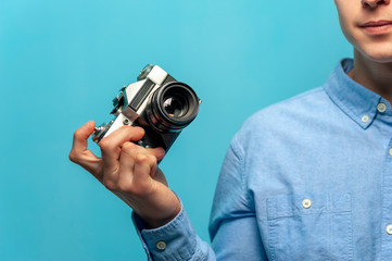 Close-up - positive young male photographer holding vintage camera