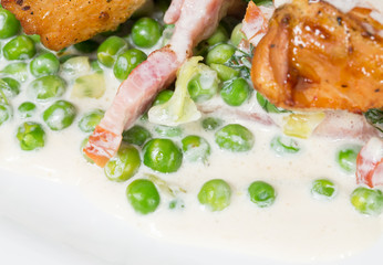 Grilled chicken fillets with bacon and peas.