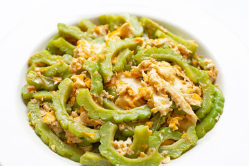 Stir-fried egg with bitter melon on a white dish on white