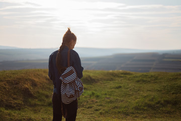 Back view of young girl with backpack in the field
